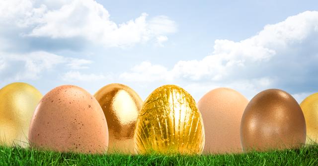 Golden Easter eggs are placed in grass, against a backdrop of a blue sky with white clouds. This concept can be used for Easter promotions, festive greetings, springtime celebrations, luxury branding, and advertising related to Easter egg hunts or holiday events.