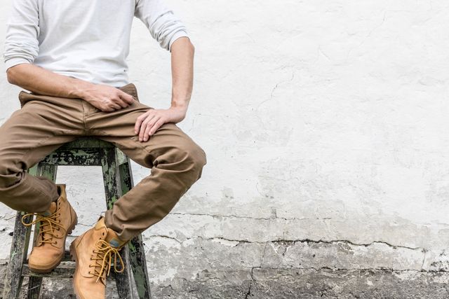 Man sitting on stool wearing casual brown pants and boots - Download Free Stock Photos Pikwizard.com