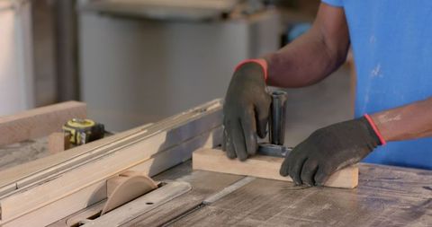 Carpenter using table saw for precise wood cutting in workshop