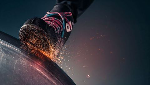 Grinding skate shoe sending sparks on metal bowl edge close-up urban action