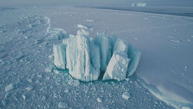 Towering fractured iceberg columns dominating arctic sea ice plain with turquoise leads