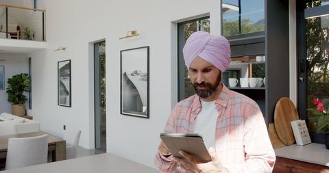 Man wearing turban using tablet in modern kitchen