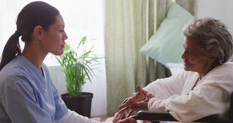 Nurse Communicating with Senior Wheelchair User at Retirement Home