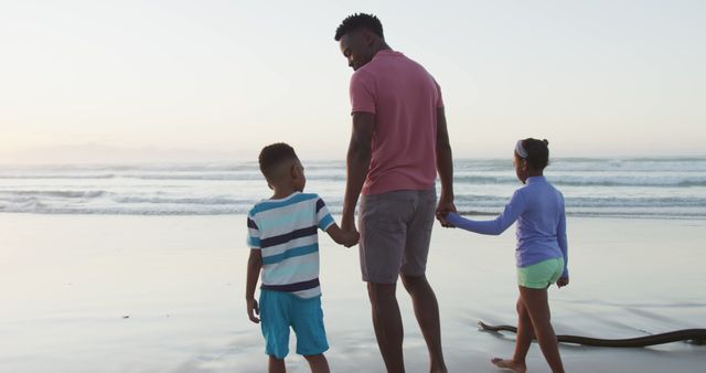 Family spends quality time walking on beach during sunset. Perfect for content on family vacations, beach holidays, parental bonding, and outdoor activities.