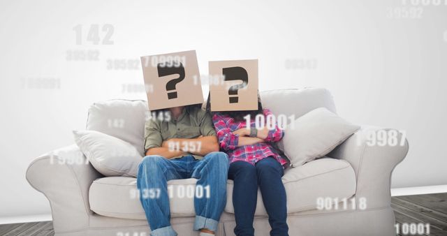 Couple sitting together on sofa with cardboard boxes on heads having question marks. Image represents concept of anonymity, confusion, and questioning identity. Useful for articles or blogs on identity issues, relationship advice, or playful conceptual themes. Could work well in editorials or advertisements focusing on mystery, uncertainty, or problem-solving.