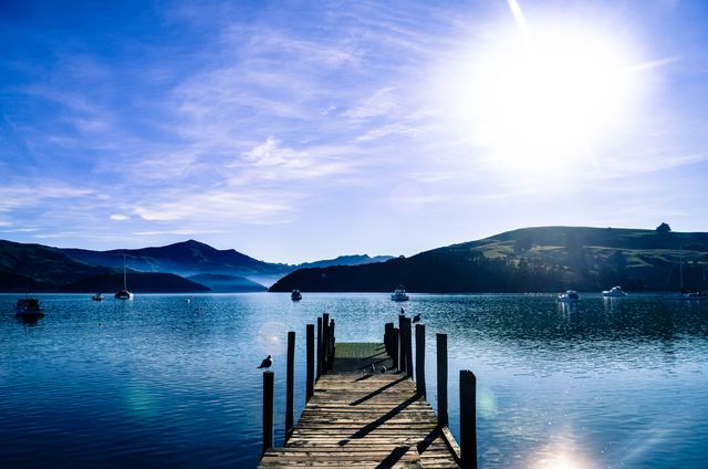 Perfect for travel blogs, nature photography, inspirational posters. Highlights serenity of early morning at a tranquil lake with a wooden pier stretching out toward calm water. Ideal for relaxation themes, vacation promotions, or motivational graphics.