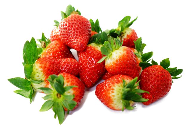 Vibrant red strawberries piled with their green leaves on white background. Ideal for health, nutrition, and organic food concepts. Suitable for food blogs, advertising, recipe illustrations, and supermarket flyers. Emphasizes freshness and natural sweetness.