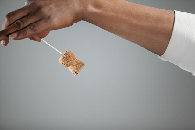 Hand holding a cork against grey background