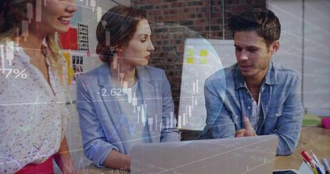 Young professionals collaborating and analyzing financial charts on laptop in modern office