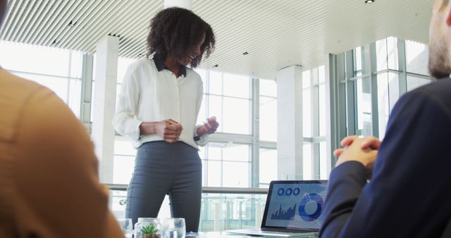 Businesswoman presenting data in the office to colleagues. Suitable for illustrating business presentations, teamwork, strategy sessions, professional communication, and data analysis.