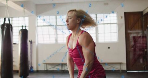 Female athlete performing hip hinge while holding weight in gym with motion tracking markers