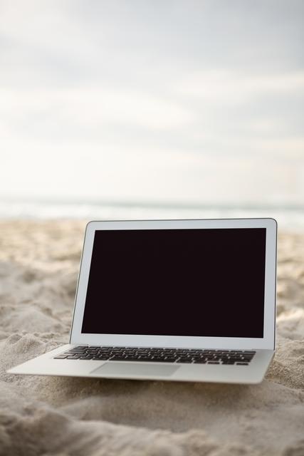 Laptop kept on sand at beach