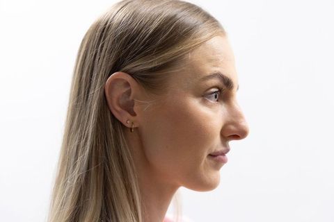 Minimalist headshot profile of blonde woman wearing gold earrings and pale pink top