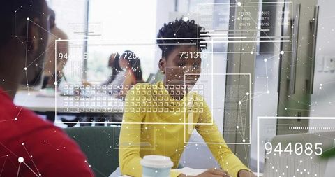 Woman reviewing documents at coworking desk wearing yellow sweater with HUD data overlay