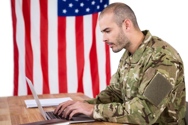 Solider using a laptop at desk against white background