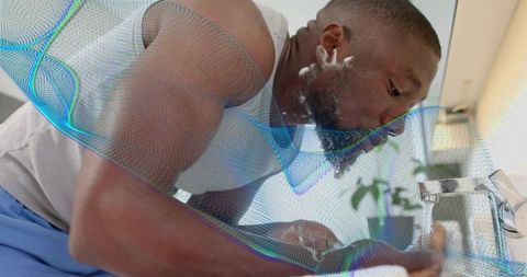 Leaning man rinsing shaving foam at modern bathroom sink with running faucet