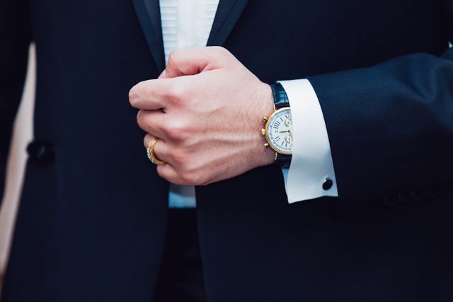 Businessman wears a sophisticated watch while adjusting his cuff. Ideal for use in professional, business, and fashion contexts. This image highlights themes of elegance, professionalism, and attention to detail, making it suitable for articles, advertisements or corporate presentations emphasizing time management, professional attire, or personal style.