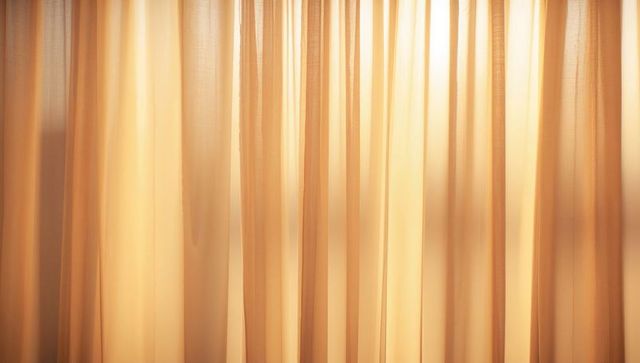 Backlit sheer curtains filtering golden sunlight through pleated beige drapery