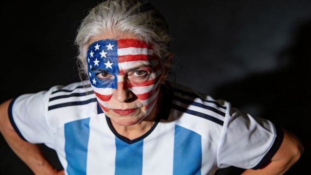 Senior woman wearing soccer jersey with usa flag face paint, dramatic patriotic portrait