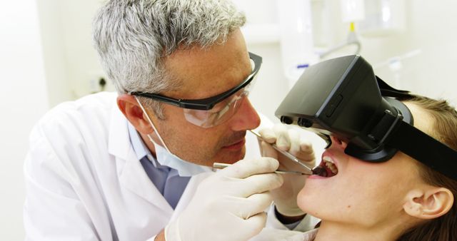 Dentist wearing a virtual reality headset while performing a dental procedure on a patient. This image illustrates the integration of advanced technology in modern dental practices, enhancing patient care and improving the experience for both doctor and patient. Ideal for articles on innovative healthcare practices, dental tech solutions, and advancements in medical technology.