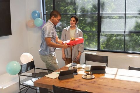 Diverse Employees Celebrating with Gift and Cakes in Office Meeting Room