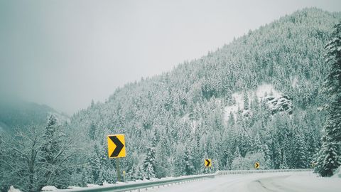 Snow-Covered Road Alongside Forested Mountain Horizon