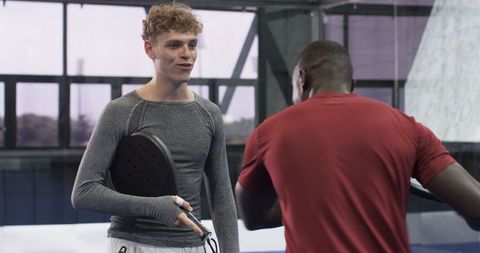 Diverse Male Athletes Engaging in Determined Padel Game in Gym
