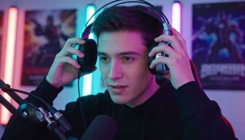Young male streamer adjusting headset while preparing live gaming stream with rgb lighting