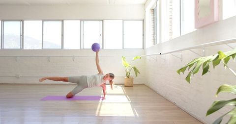 Woman Practicing Yoga with Ball in Sunlit Studio
