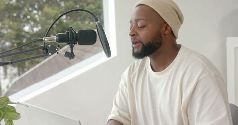 African american podcaster recording in minimalist home studio with condenser mic