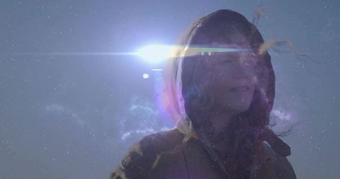 Woman in hood gazing at moonlit nebula-sky pondering solitude