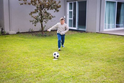 Young Boy Playing Soccer Enthusiastically on Lawn