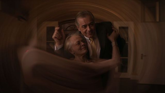 Senior couple dancing in warm living room with motion blur embracing romantic intimacy