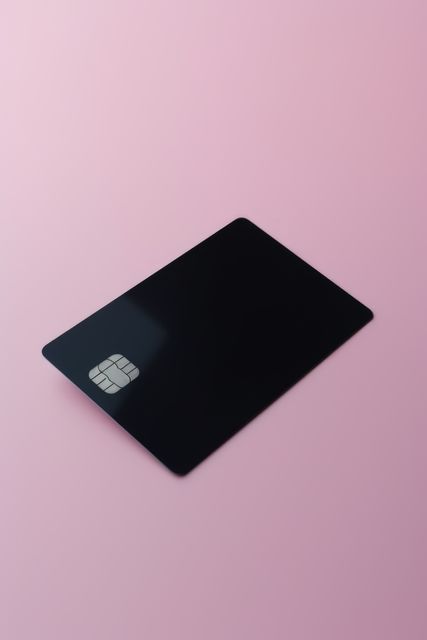 Blank black credit card with microchip on pink, copy space, created using generative ai technology. Emv chip, banking, spending, technology and finance mock up concept digitally generated image.