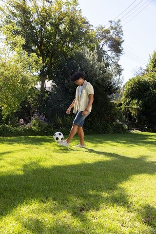 Young man engaging in casual soccer play on sunny lawn