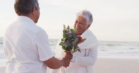 Senior Couple Enjoying Romantic Beach Moment with Flowers - Download Free Stock Images Pikwizard.com