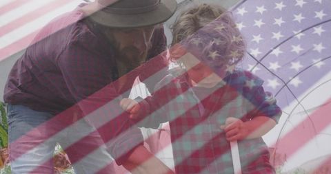 Father and son harvesting in greenhouse overlaid with us flag