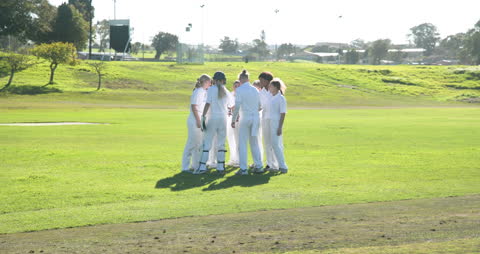 Female Cricket Team Huddling on Field Strategizing for Game