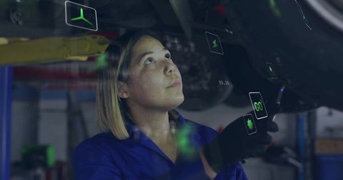 Female mechanic inspecting undercarriage using augmented reality diagnostics in auto garage