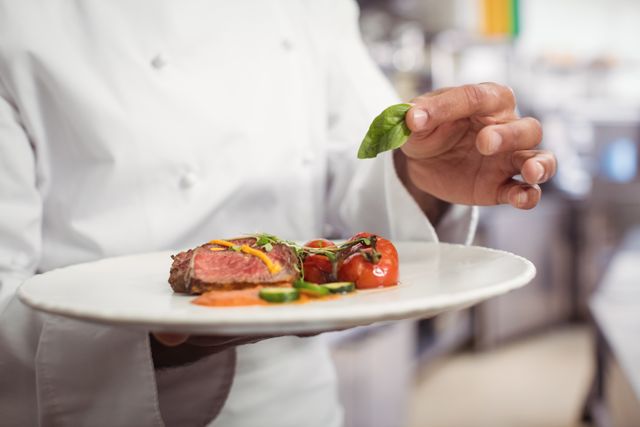 Mid section of chef holding delicious dish in kitchen at restaurant
