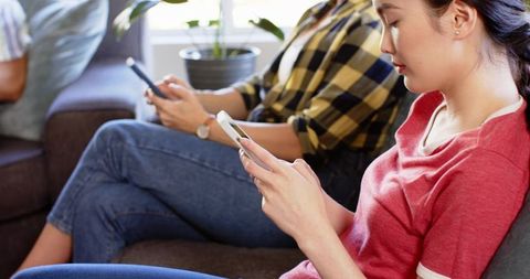 Friends Relaxing Indoors Scrolling on Smartphones Comfortably