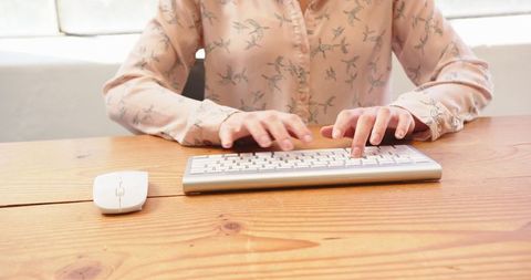 Woman typing on wireless keyboard at office desk