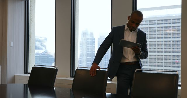 Businessman Reviewing Documents on Tablet Near Large Windows - Download Free Stock Images Pikwizard.com