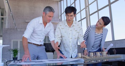 Multiethnic team reviewing architectural plans in modern office
