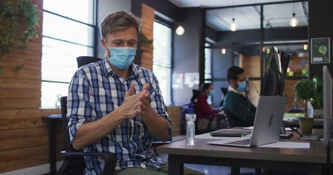Office Worker Sanitizing Hands Wearing Face Mask During Pandemic