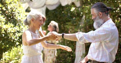 Mature couple dancing in sunlit garden holding hands with red grid overlay