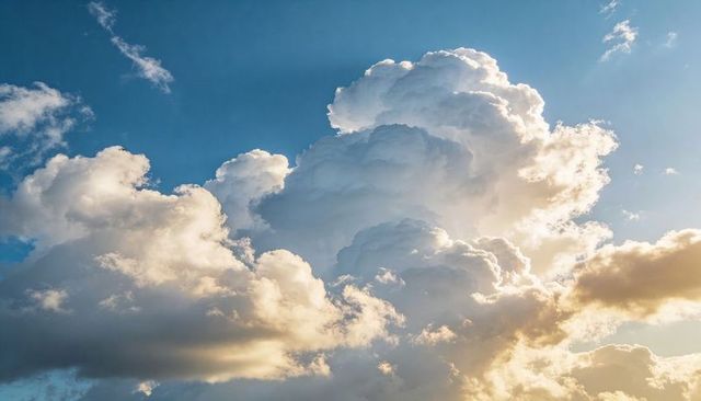Towering Cumulus Cloud Rising in Blue Sky with Golden Backlit Edges at Sunset