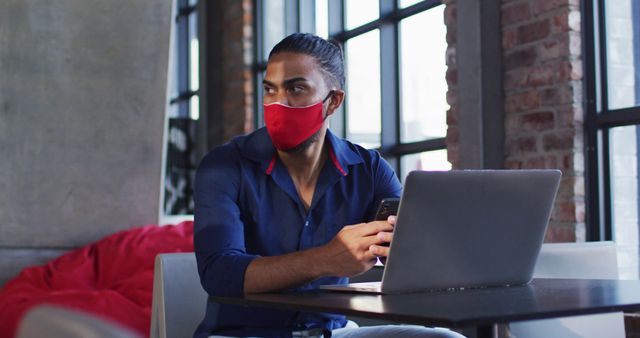 Young Man Wearing Mask Working on Laptop in Modern Cafe - Download Free Stock Images Pikwizard.com