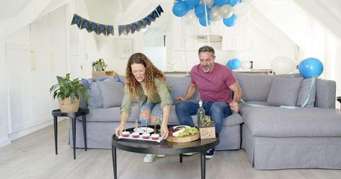 Mature Couple Celebrating Birthday at Home with Wine and Snacks
