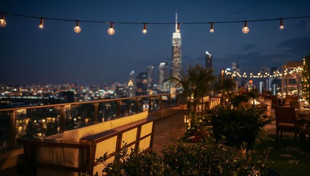 Rooftop lounge at dusk with string lights, cushioned seating and illuminated city skyline